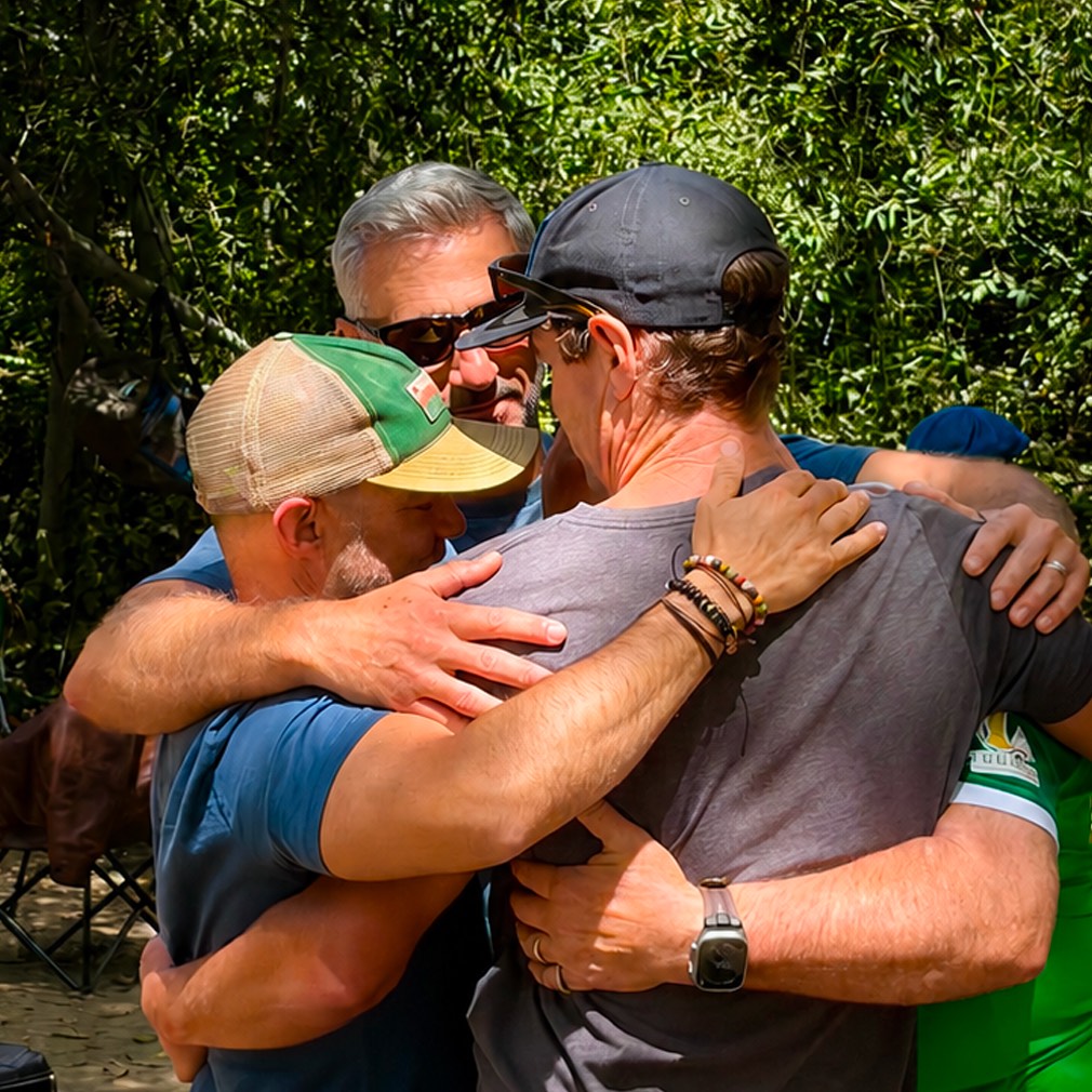 Men embracing in a group hug at a UAF retreat